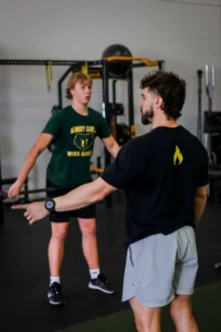 Coach instructing a young athlete during strength and conditioning training